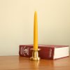 solid brass candle holder with a tall tapered dinner candle standing in front of an old book.