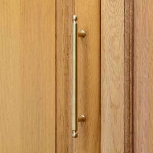 solid brass cupboard handle on a wooden cupboard door.