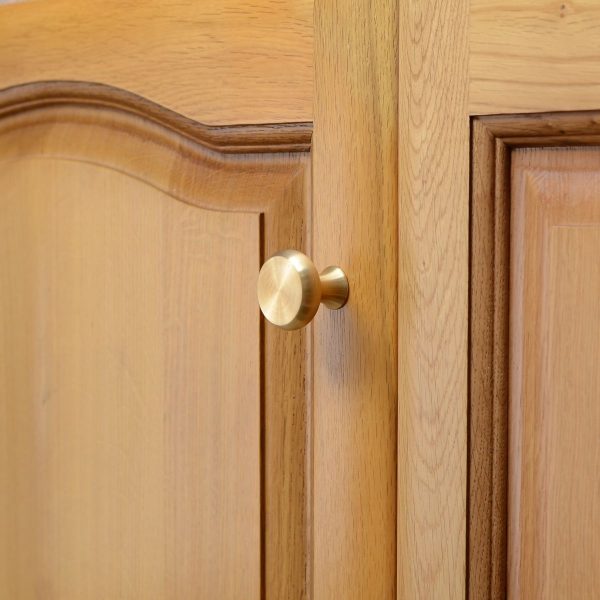 solid-brass-cupboard-knob-button-large-3 solid brass cupboard knob with button shape, mounted to wooden cupboard door.