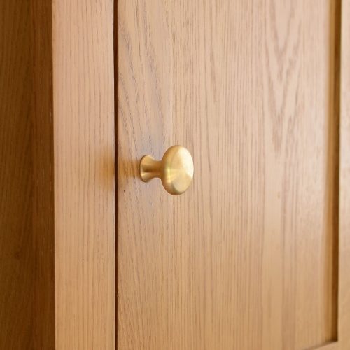 solid brass cupboard knob with classic shape, mounted to cabinet door.