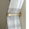 solid brass curtain holdback with pointed end, shown in use.