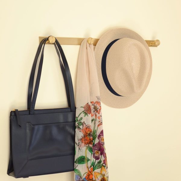 solid brass quad wall hanger hook, shown holding a bag, a hat and a scarf.